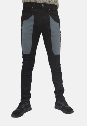 Jeans neri con pannelli in tessuto grigio sui taschini anteriori. Design slim fit con una texture liscia e hardware denim standard.
