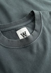 Czarna bawełniana koszulka z okrągłym dekoltem, z przeszytymi brzegami i metką z napisem "AW". Gładka tekstura i prosty design.