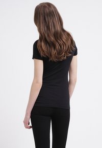 Černé tričko s krátkým rukávem vyrobené z jersey látky, obtažený design, hladká textura a bez vzorů či ozdob.