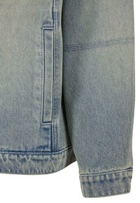 Svijetloplava traper jakna s opuštenim krojem, koja ima vidljivu džep, kontrastnu šavovi i lagano izlizano porub. Glatka tekstura, ležeran dizajn.