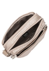 Light beige Kipling bag with multiple zippered compartments, smooth fabric, and a textured zipper trim. Features a small charm on the side.