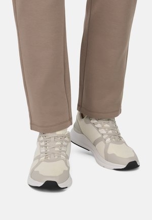 Zapatillas de running ligeras en beige y blanco, con parte superior de malla, suelas gruesas y detalles en gris. Pantalones de corte relajado en un tejido suave beige.