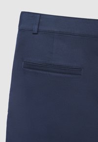 Pantaloni blu navy in tessuto liscio, con cintura, tasca posteriore con apertura dritta e dettagli di cuciture ordinate.