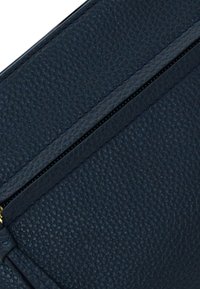 Clutch in pelle blu navy con una finitura testurizzata, dotato di chiusura con zip e dettagli di cucitura discreti lungo i bordi.