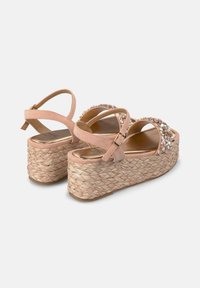 Sandales compensées en suède rose avec semelles en jute tressé, ornées de pierres décoratives sur les brides et de boucles de cheville réglables.