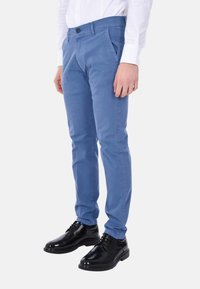 Pantaloni azzurri chiari in cotone. Design slim fit, davanti piatto e tasche laterali discrete. Abbinati a scarpe eleganti in pelle nera.