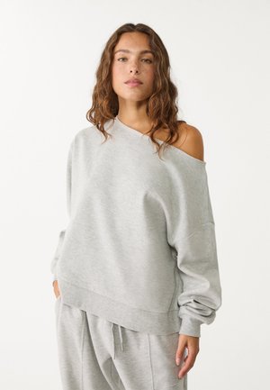 Lys grå oversized sweatshirt med off-shoulder design, ribbede manchetter og kant. Fremstillet af blødt stof med en glat tekstur.