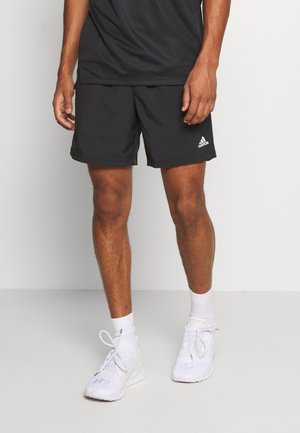 Czarne sportowe szorty z elastycznym paskiem w talii, z białym logo Adidas. W komplecie białe trampki i skarpetki do kostek.