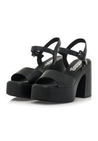 Sandalias de plataforma negras con diseño de punta abierta, amplia correa frontal y correa ajustable en el tobillo. Material sintético suave y tacón grueso.
