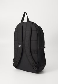 Zwarte nylon rugzak met een gevoerde achterkant en verstelbare banden, voorzien van een mesh zijvak en een logo-opdruk op de voorkant.