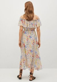 Robe maxi florale, décolletée, avec un col à volants, dans des couleurs pastel, et une taille cintrée. Tissu léger et fluide avec une texture douce.