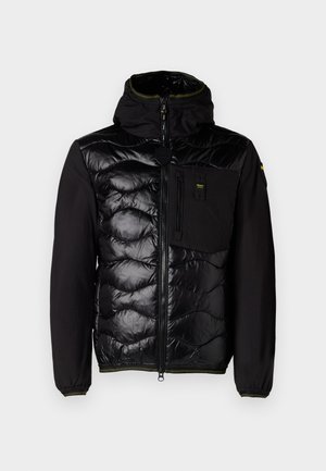 Veste noire isolante avec un devant matelassé, une capuche et des poches zippées. Caractérisée par un corps en tissu lisse et des poignets élastiques avec des accents verts.