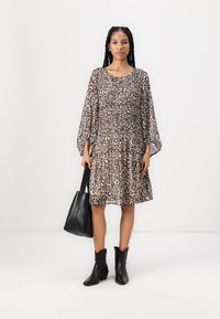 Haljina s leopard uzorkom, dugim napuhanim rukavima, labavog kroja i naboranim strukom. Uparen s crnim čizmama do gležnja i velikom crnom torbom.