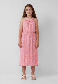 Ein ärmelloses, rosa, blumenmusterndes Kleid mit gerafftem Ausschnitt, elastischem Bund und fließendem Midikleid. Kombiniert mit leichten Sandalen.