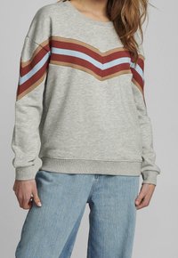 Sweatshirt gris présentant un motif chevron côtelé en rouille, marron et bleu clair. Manches longues et encolure ronde. Texture douce.