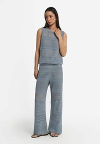 Ljusblå stickad tanktop och vida byxor, med en texturerad design som har öppna partier och en avslappnad passform.