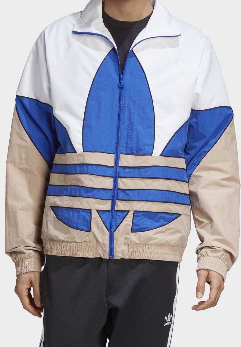 Windbreaker jacket in white, blue, and beige. Features a zip front, elastic cuffs, and bold graphic design with horizontal stripes and rounded accents.