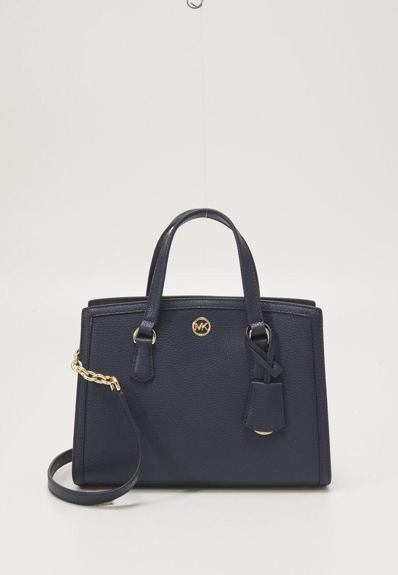 Sac à main en cuir bleu marine avec double poignée supérieure, logo MK doré, bandoulière amovible avec détail en chaîne dorée, et étiquette en cuir attachée.