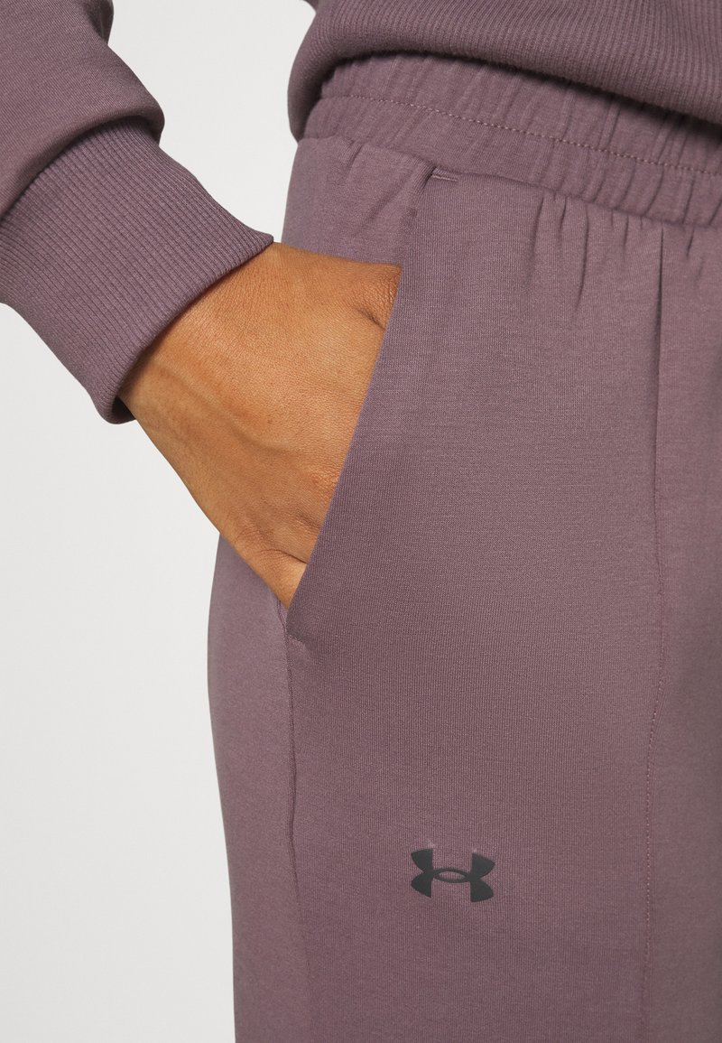 Hand ruht in der mauvefarbenen Unterwäsche-Hose von Under Armour, wobei der gerippte Bund und die elastische Taillenbund-Details zu sehen sind.