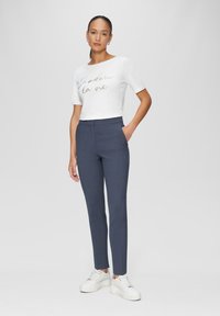 T-shirt blanc court avec "J'adore la vie" imprimé en paillettes, associé à un pantalon slim-fit navy et des baskets blanches. Tissu lisse et design ajusté.