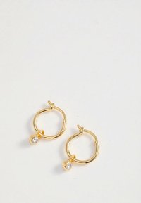 Pair of small gold hoop earrings each with a single small dangling clear gemstone on a white background.