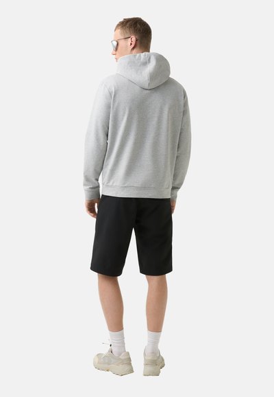 Grauer Kapuzenpullover mit Kordelzug und lässiger Passform, kombiniert mit schwarzen Shorts. Das Outfit wird durch helle Sneakers und weiße Socken ergänzt.