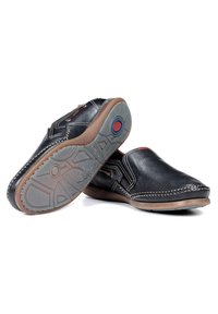 Zwarte leren instapschoenen met een ronde neus, contrasterende stiksels en een rubberen zool met een patroon en een blauwe cirkelvormige detail.