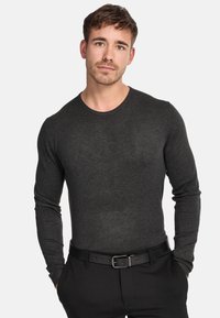 Chemise à manches longues gris foncé avec un col rond, coupe ajustée et texture lisse, associée à un pantalon noir et une ceinture.