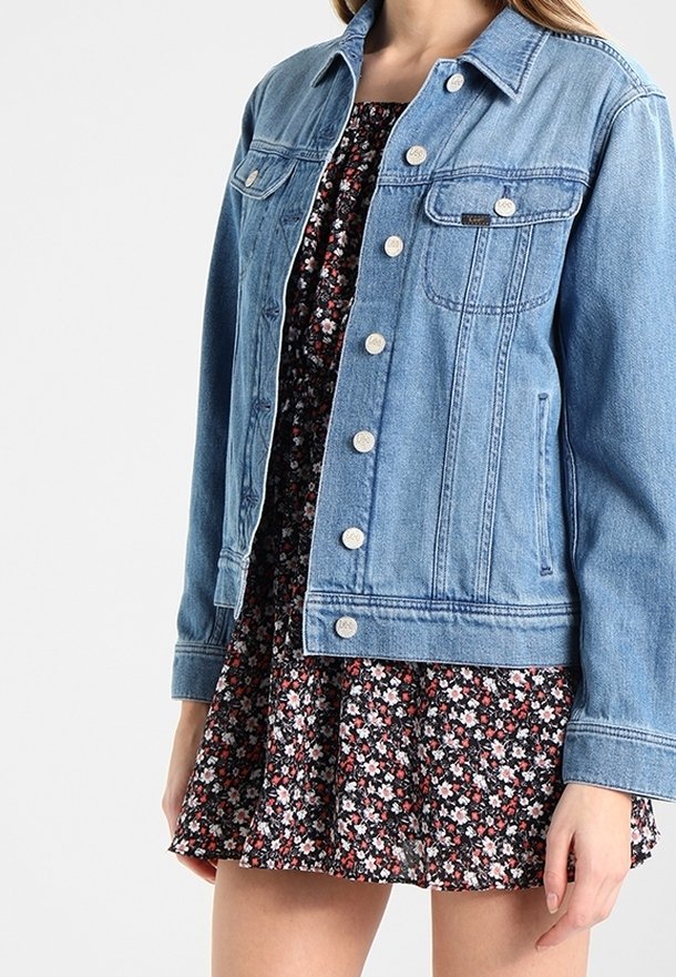 Ljusblå denimjacka med krage, silverknappar, framfickor och rak passform, kombinerad med en blommig klänning.