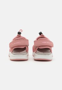 Rozā sandales ar mīkstu materiālu, atvērtu aizmuguri, regulējamām siksnām un baltu zoli. Iekļautas ir vilkšanas cilpas vieglai uzvilkšanai.