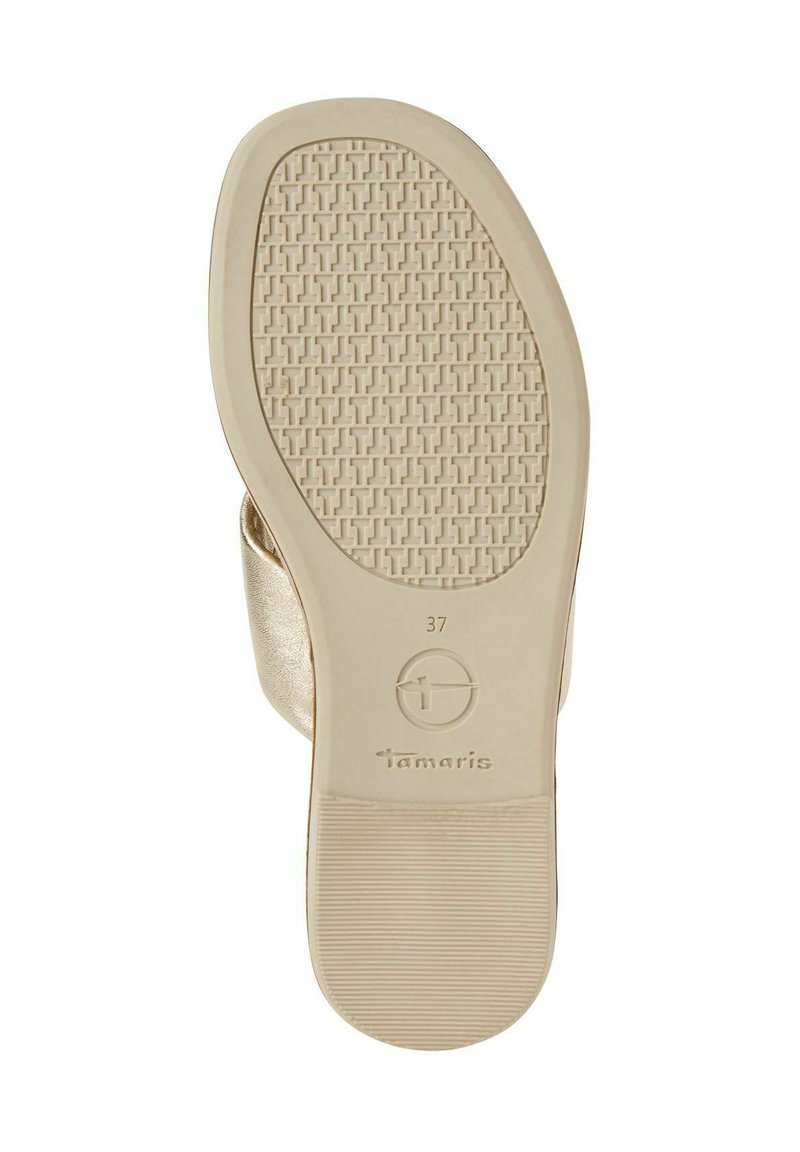 Zool van een schoen, gekenmerkt door een gestructureerd beige rubberen oppervlak met een rasterpatroon. Bevat 'Tamaris' branding en maat 37 gedrukt aan de zijkant.