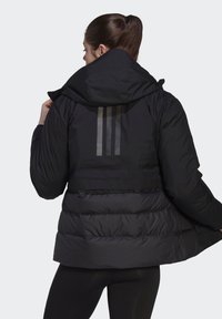 Black puffer jacket with a hood, featuring a quilted design, elastic waist, and three vertical reflective stripes on the back.