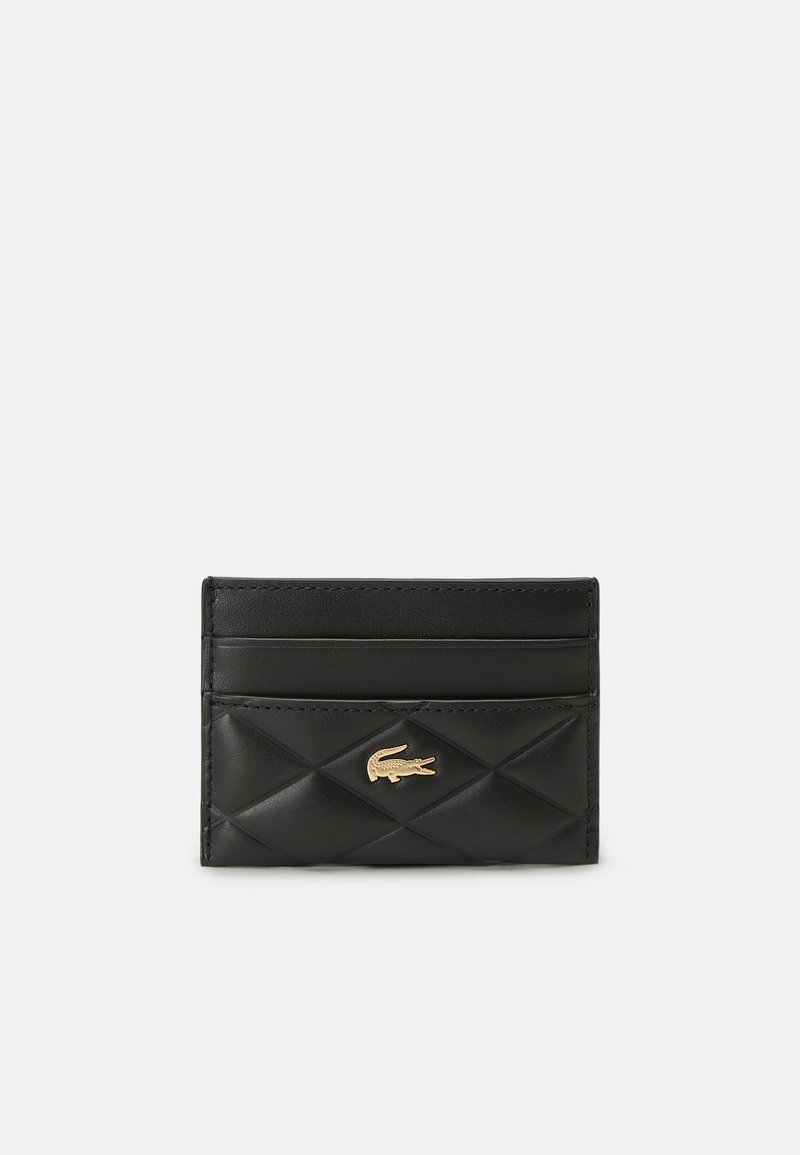 Porte-cartes en cuir matelassé noir avec trois fentes pour cartes et un petit logo crocodile doré au centre avant.