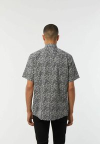 Korte mouwen shirt in zwart-wit bloemenprint, met een kraag, rechte zoom en lichtgewicht stof. Achteraanzicht weergegeven.
