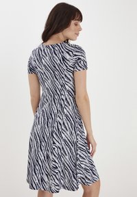 Sukienka z krótkim rękawem w granatowo-białym kolorze z wzorem w zebry, rozkloszowany dół, gładki materiał i okrągły dekolt.