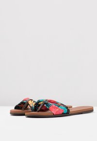 Infradito con stampa floreale su sfondo nero, con suola marrone texturizzata e morbidi cinturini intrecciati in colori vivaci.