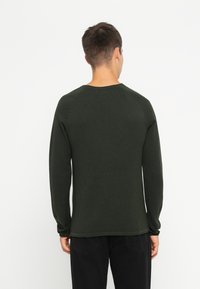 Cămașă lungă de culoare verde închis, cu guler rotund, dintr-un material texturat și cu un design ajustat. Finisaj neted, cu manșete și tiv cu dantelă.