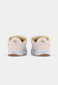 Baskets Puma roses claires vues de l'arrière, avec des rayures blanches, une doublure intérieure beige et des semelles couleur gomme.