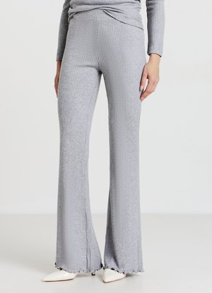 Grau gerippte, ausgestellte Strickhosen mit enger Passform und dezenten ausgefransten Saumdetails, kombiniert mit spitzen weißen High Heels.