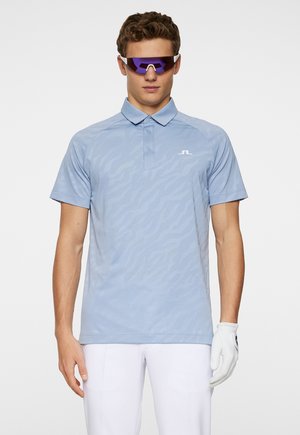 Light blue polo shirt with a textured, subtle wave pattern, featuring a three-button placket and a small white logo on the chest.