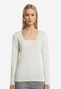 Vit långärmad tröja med fyrkantig halsringning och ribbad manschettdetalj. Mjuk textur, lätt material, minimalistisk design.