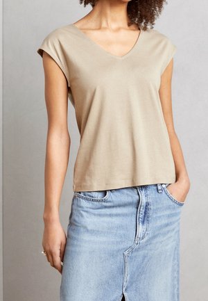 Beige bomulds V-hals t-shirt med korte ærmer, afslappet pasform, blød tekstur, kombineret med en lys blå denimnederdel med en slids foran.