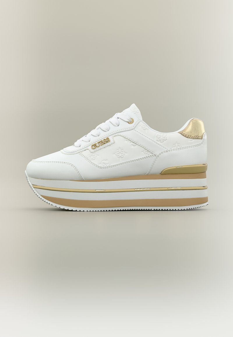 Λευκό και χρυσό πλατφόρμα αθλητικό παπούτσι με κορδόνια, ανάγλυφο σχέδιο με λογότυπο και ετικέτα "GUESS" στο πλάι.