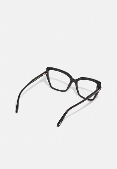 Gafas rectangulares negras con un acabado brillante. Cuentan con montura gruesa y brazos delgados y afilados con acentos dorados en las bisagras.