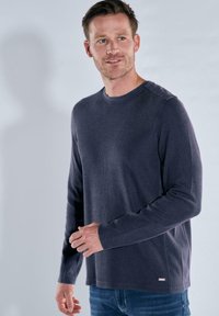 Dunkelblaues Longsleeve-Shirt mit Rundhalsausschnitt, das über einen strukturierten Stoff und gerippte Akzente an den Schultern verfügt. Slim-Fit und lässiges Design.