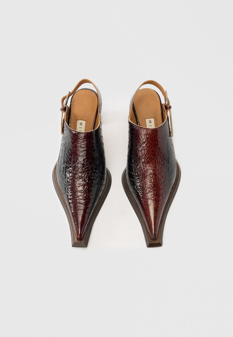 Zapatos slingback de punta afilada hechos de cuero texturizado rojo oscuro con un acabado liso. Presentan un tacón delgado y una correa ajustable en el tobillo.