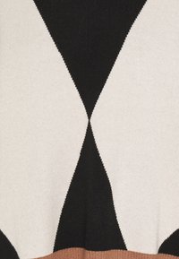 Pull avec un motif audacieux en losanges noirs, beige et crème. Texture tricotée avec un ourlet côtelé. Design confortable et moderne.