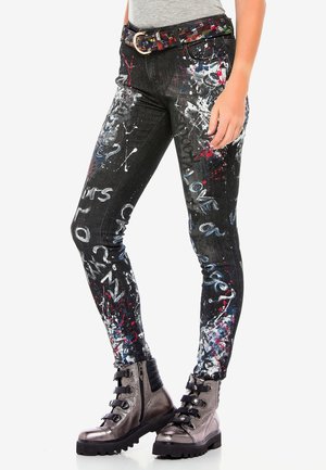Svarta jeans i denim med ett sprutmålningdesig i vitt, blått och rött. Kombinerat med metalliska grå kängor.