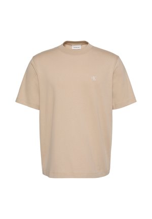 Beige short-sleeve crewneck T-shirt with small white "cK" logo on left chest and Calvin Klein Jeans label inside collar.