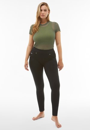 Top in maglia a righe verdi con maniche corte e scollo rotondo, abbinato a leggings neri aderenti con tasche con cerniera.